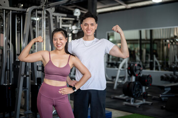 Two sporty Asians, a male and female are confidently showing a power gesture with their arms.