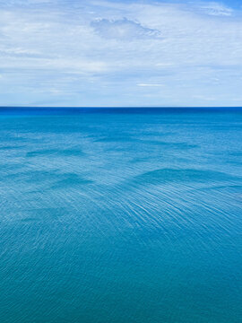 Blue sea calm rippled water and cloudy sky.
