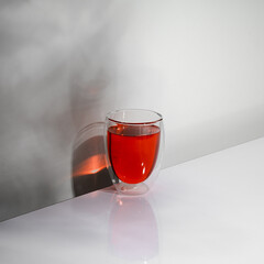 Closeup of a glass of red wine isolated on a table with leaf shadow.
