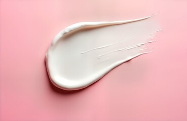 Cosmetic cream smudge displayed on pink backdrop. Creamy white texture spreads out in dynamic shape. Abstract beauty product sample shows skincare lotion. Studio shot captures beauty care product.