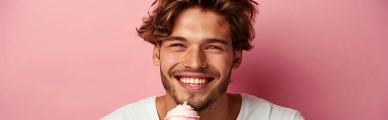 Fototapeta premium Young Man Smiling Holding Ice Cream against Pink Background