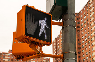 Semáforo peatonal en una calle de Nueva York, barrio de Harlem, USA. Semáforo con silueta de caminar iluminada en blanco indicando la posibilidad de cruzar la calle el peatón.