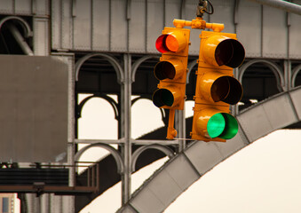 Semáforo para vehículos en una calle de Nueva York, USA. Semáforo colgante de un cruce de calles con uno en rojo y otro en verde. Semáforo en el barrio de Harlem junto al puente del metro en Broadway.