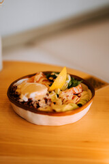 Delicious salmon bowl with boiled red rice, creamy avocado, poached egg, cucumber, lettuce, and homemade Caesar sauce