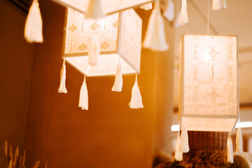 Beautifully crafted decorative lanterns hang from the ceiling in a cozy indoor setting during a warm afternoon