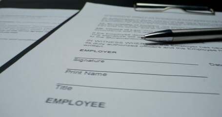 The documents are on the table, close-up. An employment contract. The pen is on the paper