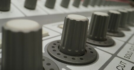 A man controls a mixing console while recording audio in the studio. Close-up of his hand, an...