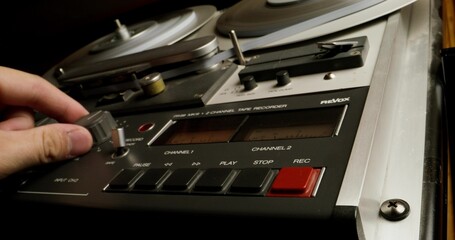 Obraz premium A man controls a professional tape recorder for recording on magnetic tape. Close-up of his hands, an unrecognizable person. Recording Studio