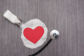 Salt pouring from salt shaker over red heart and stethoscope, cardiovascular health risk concept