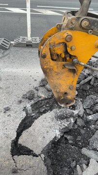 Close up view of excavator bucket digging the road surface.
