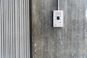 real photography of an intercom with surveillance camera on a textured concrete wall with industrial style and copy space