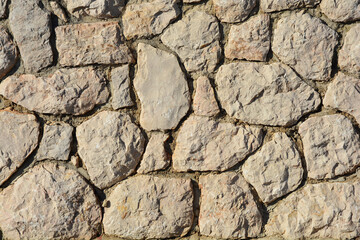 Detail of a wall made of natural, irregularly shaped stones, creating a rustic and textured surface