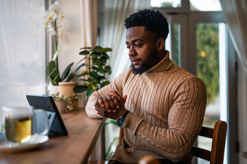 Freelancer using digital tablet to communicate online. He is sitting in bar and having online...