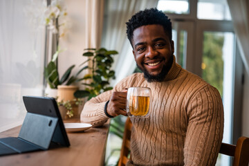Young man using digital tablet to communicate online. He is sitting in bar,drinking tea and having video call.