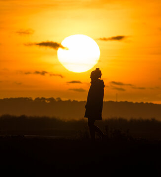Fototapeta Femme seule photographiée au téléobjectif devant un coucher de soleil