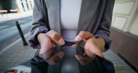 A woman in formal clothes uses a mobile phone walking along a city street. Close-up of a mobile phone screen, an unrecognizable person