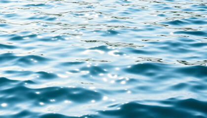 A close-up shot of the deep blue ocean with gentle waves rippling across the surface, capturing the beauty of water and the movement of the sea under bright sunlight.