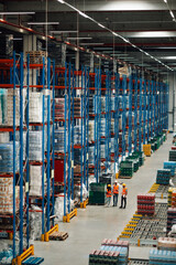 Warehouse workers checking inventory and discussing logistics in large distribution center