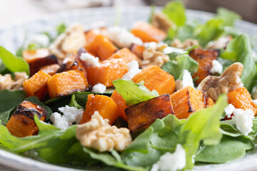 Pumpkin salad with arugula, walnuts and feta cheese on wooden. Close up
