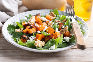 Pumpkin salad with arugula, walnuts and feta cheese on wooden