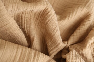 Texture of crumpled linen fabric under natural light in peach fuzz color