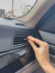 Close-up of a woman's hand adjusting air conditioning in a car