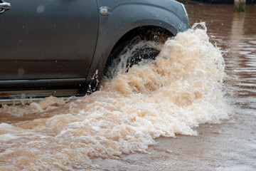 Muddy rain from a heavy rainy season flooded main roads connecting the district, making it difficult for cars to pass through and causing engine failures, in motion, car insurance concept, in motion.