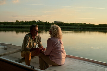 Senior couple holding hands and enjoying a romantic sunset boat ride