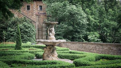 Formal Garden with a Fountain and a Stone Building.