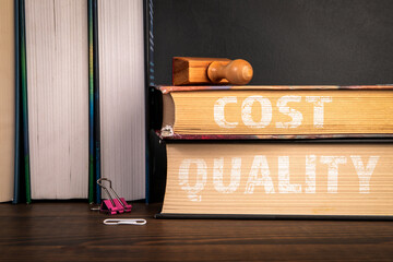 Cost and Quality.  A stack of books on a wooden shelf
