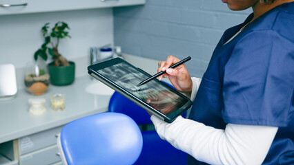 Dental Professional Viewing Patient's X-Ray on Tablet in Modern Clinic