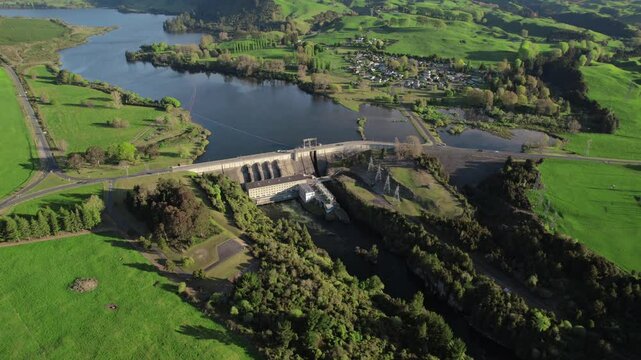 Aerial hydroelectric dam with reservoir and lush hills in Whakamaru, New Zealand