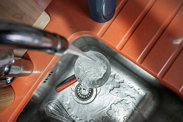 A good stream of hot water falling from the tap onto some containers that need to be washed inside...