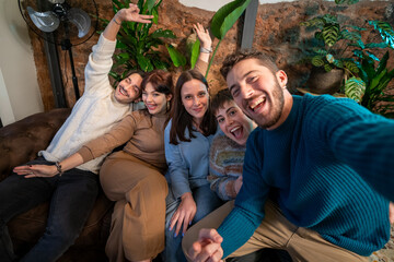 A happy group of diverse friends taking a selfie and laughing in a cozy indoor setting. A joyful,...