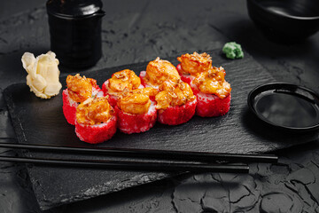 Delicious sushi rolls with shrimp and spicy sauce prepared on a slate platter in a modern dining setting