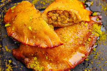 Delicious sweet pastries filled with nuts and drenched in syrup on a dark plate