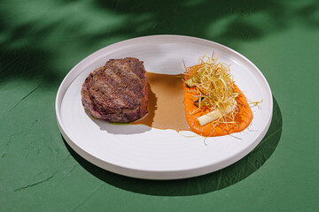 Juicy grilled steak served with vibrant puree and fresh garnish at a culinary event outdoors