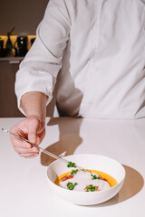 Culinary artist plating a gourmet dish with precision in a modern kitchen at twilight
