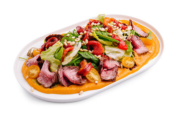 Fresh salad with grilled meat, colorful vegetables, and rich sauce served on a white platter