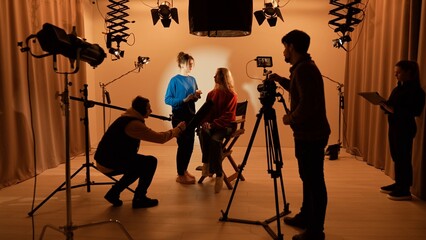Studio for photo video production with lighting equipment and cyclorama, team members preparing...