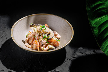 Gourmet seafood dish featuring shrimp and mussels topped with herbs served in an elegant bowl