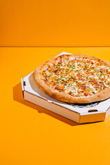 Delicious pizza with a golden crust and toppings on a vibrant yellow background