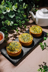 Delightful herbal tarts served alongside tea on a rustic table with greenery accents