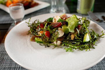 Healthy vegetable salad with fresh tomatoes, cucumbers, onions, spinach, lettuce and sesame seeds on a plate. Diet salad.