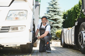 Truck repair service. Mechanic works with tire in truck workshop