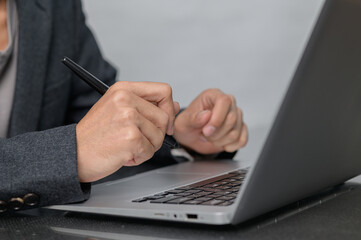 Business Professional Writing Notes on Laptop at Office Desk