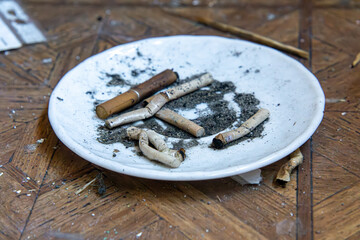 various cigarette butts on a white plate. extinguished cigarettes. cigarette ash on a plate.