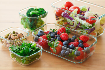 Healthy vegan food preparations for week in glass containers. Vegetables, nuts, berries in boxes.