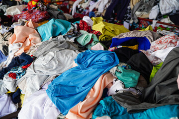 A large pile of used clothing in various colors and styles. A messy collection of secondhand...