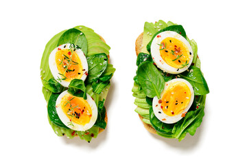 Healthy toast with sliced avocado, boiled eggs, spices and fresh spinach. Delicious breakfast or snack isolated on white background, top view